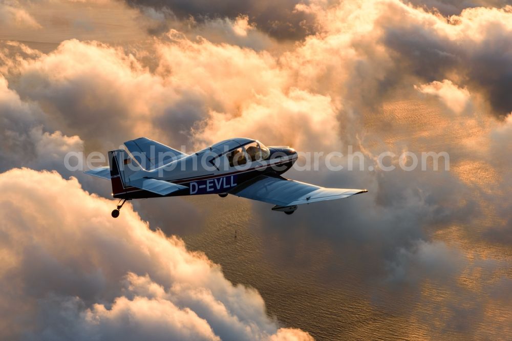 Aerial photograph Cuxhaven - Motor aircraft and sports aircraft flying above clouds in the evening light of sunset over the airspace in Cuxhaven in the federal state of Lower Saxony, Germany