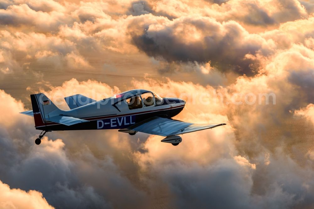 Cuxhaven from above - Motor aircraft and sports aircraft flying above clouds in the evening light of sunset over the airspace in Cuxhaven in the federal state of Lower Saxony, Germany