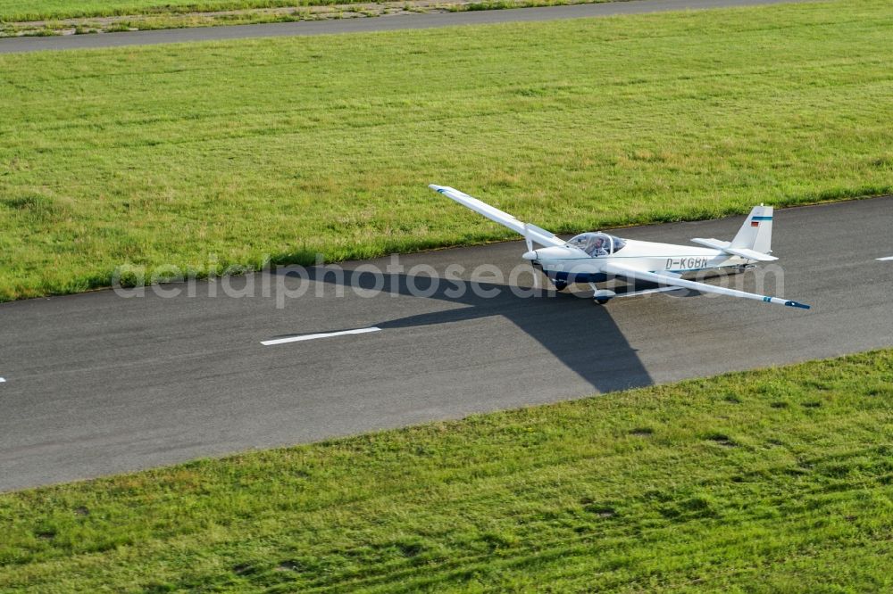 Stade from the bird's eye view: Powered glider aircraft Scheibe SF-25 in landing approach for landing at the airport in Stade in the state Lower Saxony, Germany