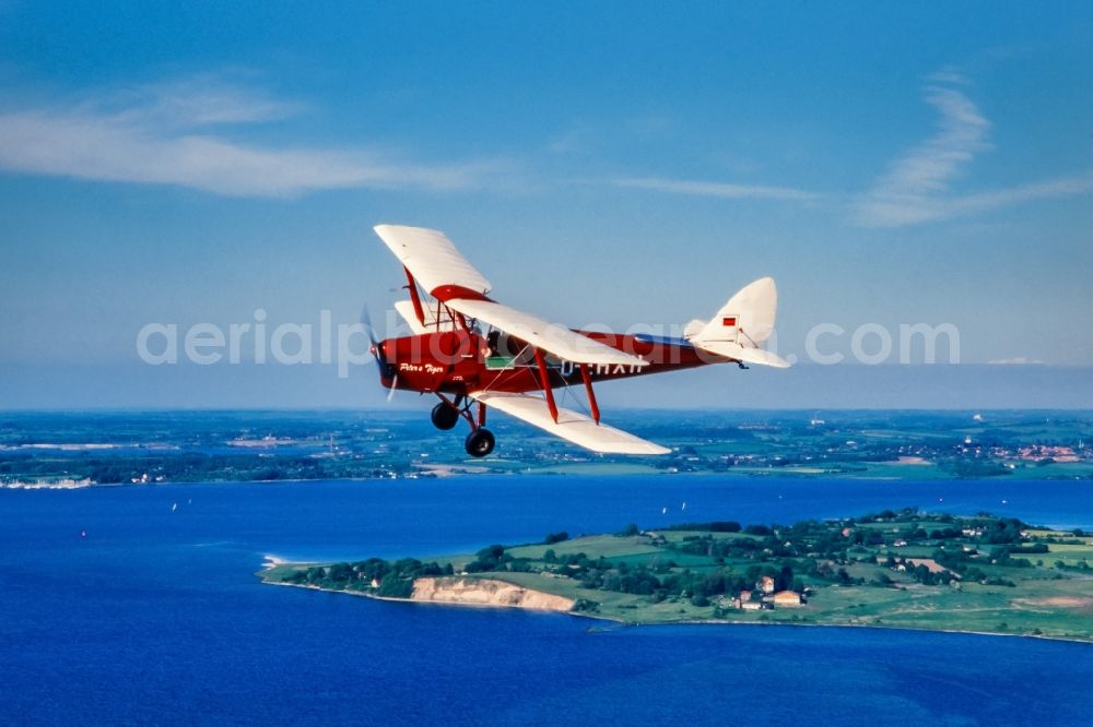 Aerial photograph Glücksburg - Vintage plane in flight over the Baltic Sea in the Flensburg Fjord airspace in Schleswig-Holstein. Historical biplane De Havilland DH-2 Tiger Moth with registration D-EHXH