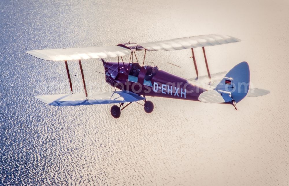 Glücksburg from the bird's eye view: Vintage plane in flight over the Baltic Sea in the Flensburg Fjord airspace in Schleswig-Holstein. Historical biplane De Havilland DH-2 Tiger Moth with registration D-EHXH
