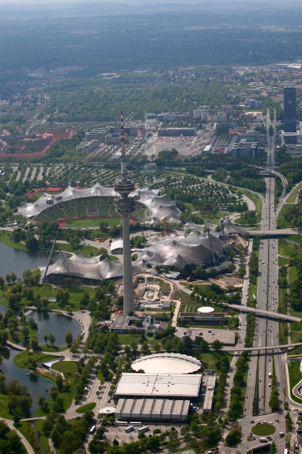 München from the bird's eye view: The Olympic Stadium in Munich, the Olympic Tower, the Olympic Hall and the Olympic lake are the key elements of the central sports facility Olympic Park and were the main locations in the 1972 Summer Olympics in Munich in Bavaria. The sports facilities are located along the four-lane thoroughfare Georg-Brauchle-Ring. The great hall below the Olympic Tower, the Olympic Ice Sports Center, which consists of the Olympic Ice Stadium, the SoccArena and a training hall. The Eisport Stadium is the venue of the DEL team Red Bull Munich
