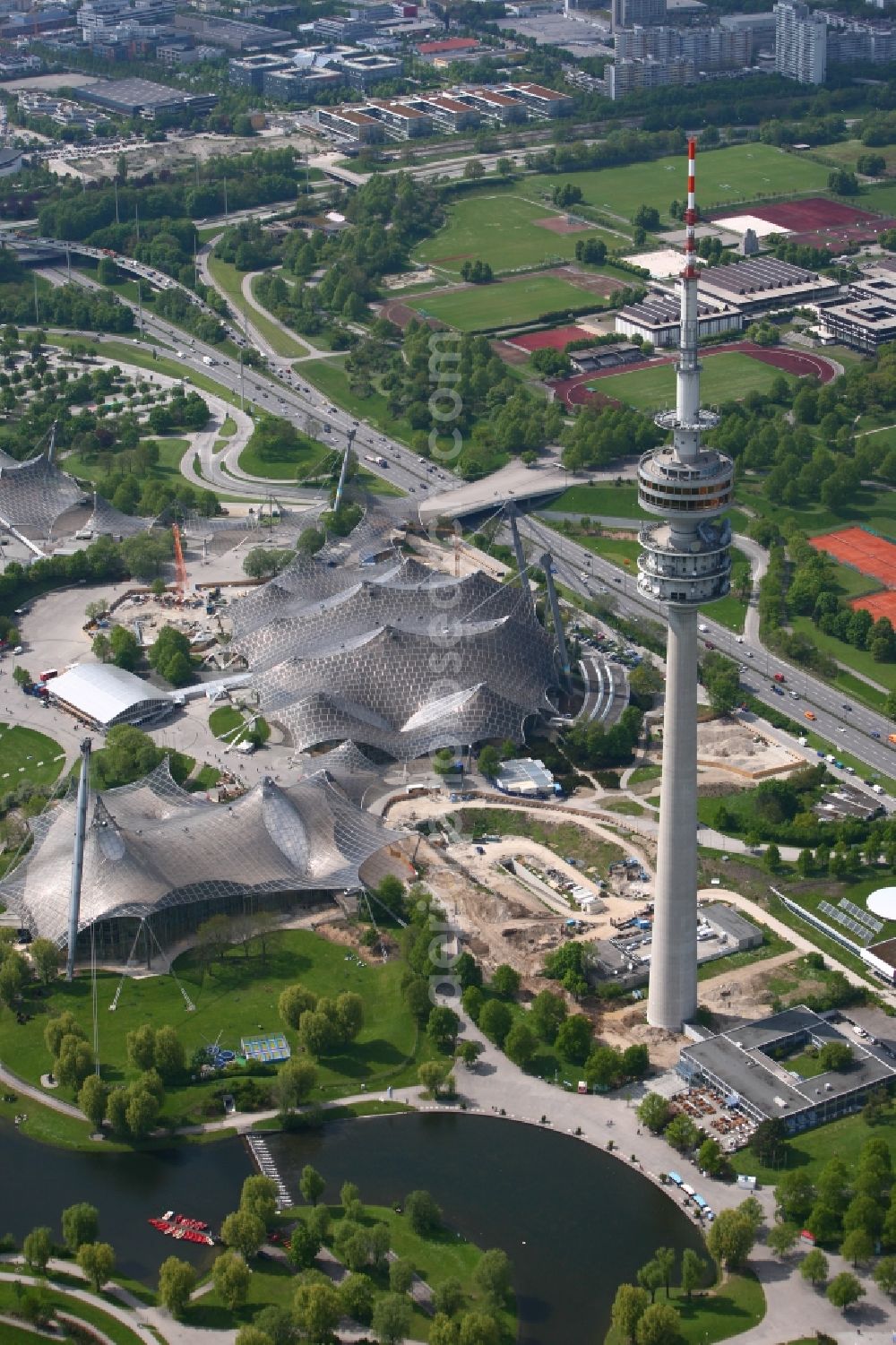 München from above - The Olympic Hall, Olympic Tower and the Olympic lake are the key elements of the central sports facility Olympic Park and were the main locations in the 1972 Summer Olympics in Munich in Bavaria. The group of architects designed the modern Olympic Park Sports and event facilities as part of landscaping within the meaning of the concept of Olympic Games in the countryside. At the foot of the TV tower is the restaurant-Olympiasee. In the background the central sports facilities at the Technical University of Munich can be seen