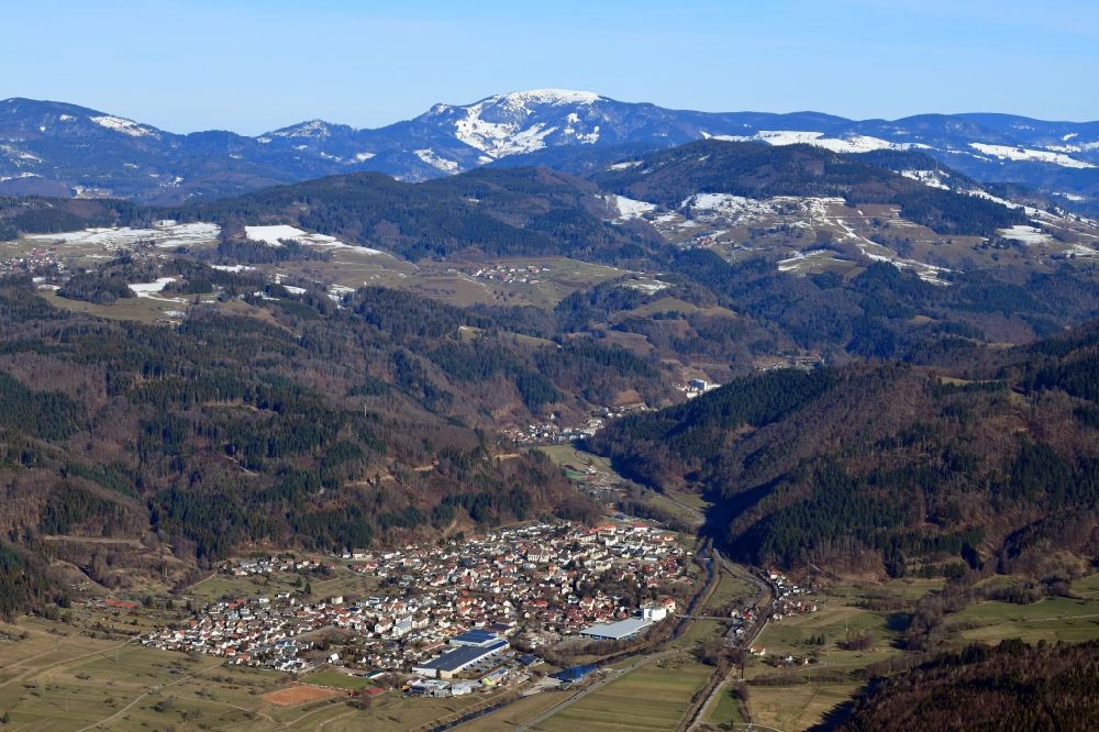Aerial image Hausen im Wiesental - Location view of residential areas in the valley landscape surrounded by mountains in Hausen im Wiesental in the state Baden-Wurttemberg, Germany. The bald summit of the Belchen in the Black Forest is still snow covered