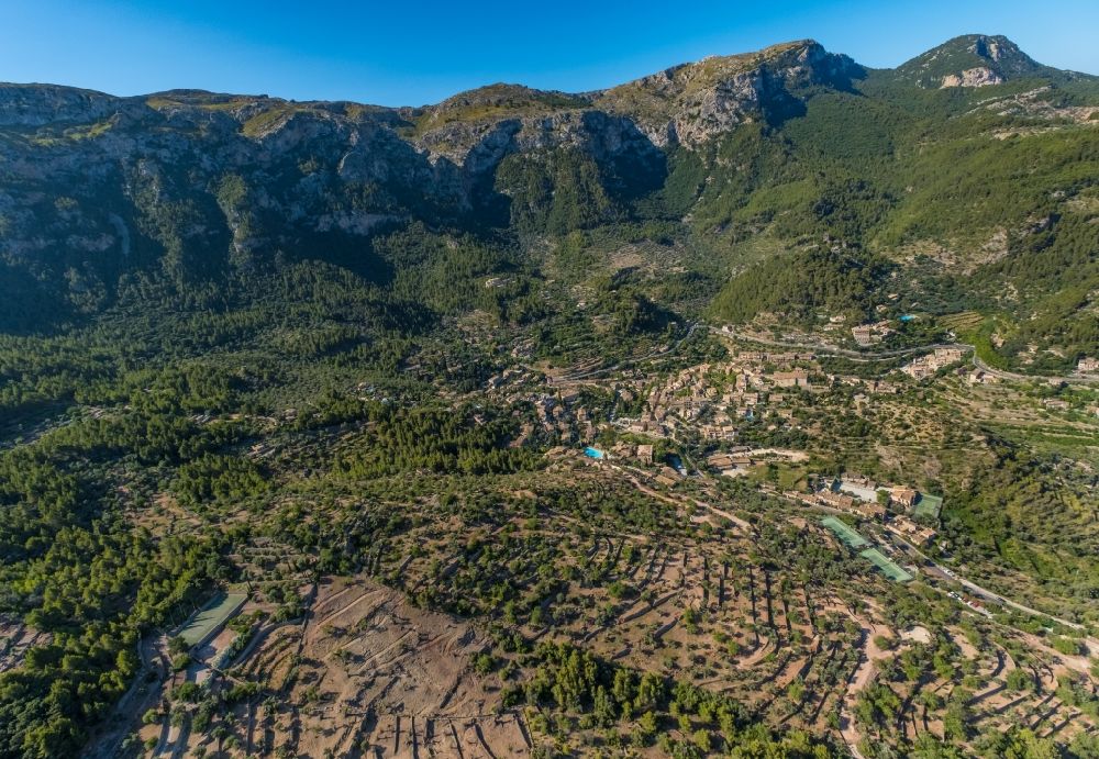 Aerial image Deia - Location view of the streets and houses of residential areas in the valley landscape surrounded by mountains and forest in Deia in Balearic island of Mallorca, Spain