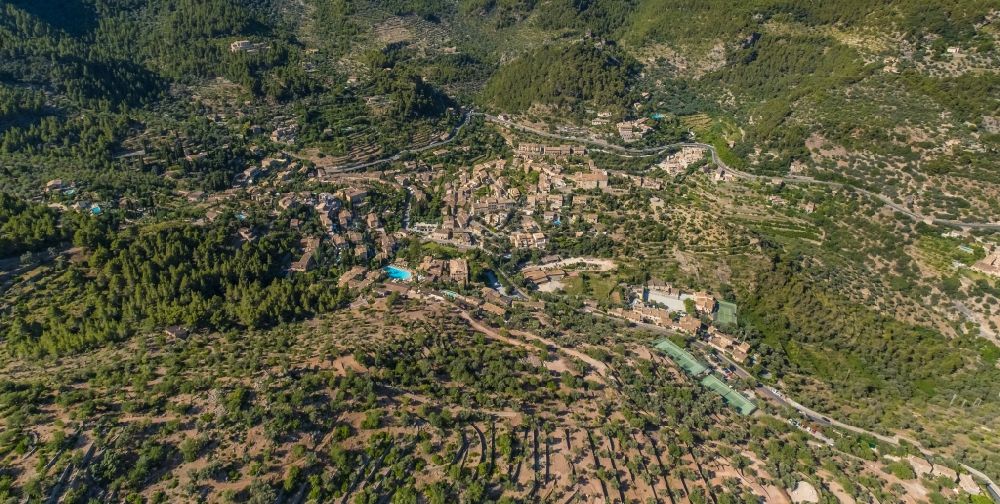 Aerial photograph Deia - Location view of the streets and houses of residential areas in the valley landscape surrounded by mountains and forest in Deia in Balearic island of Mallorca, Spain