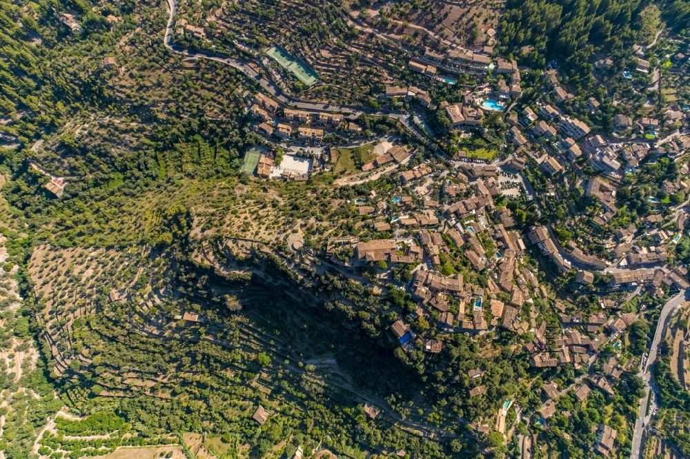 Aerial image Deia - Location view of the streets and houses of residential areas in the valley landscape surrounded by mountains and forest in Deia in Balearic island of Mallorca, Spain
