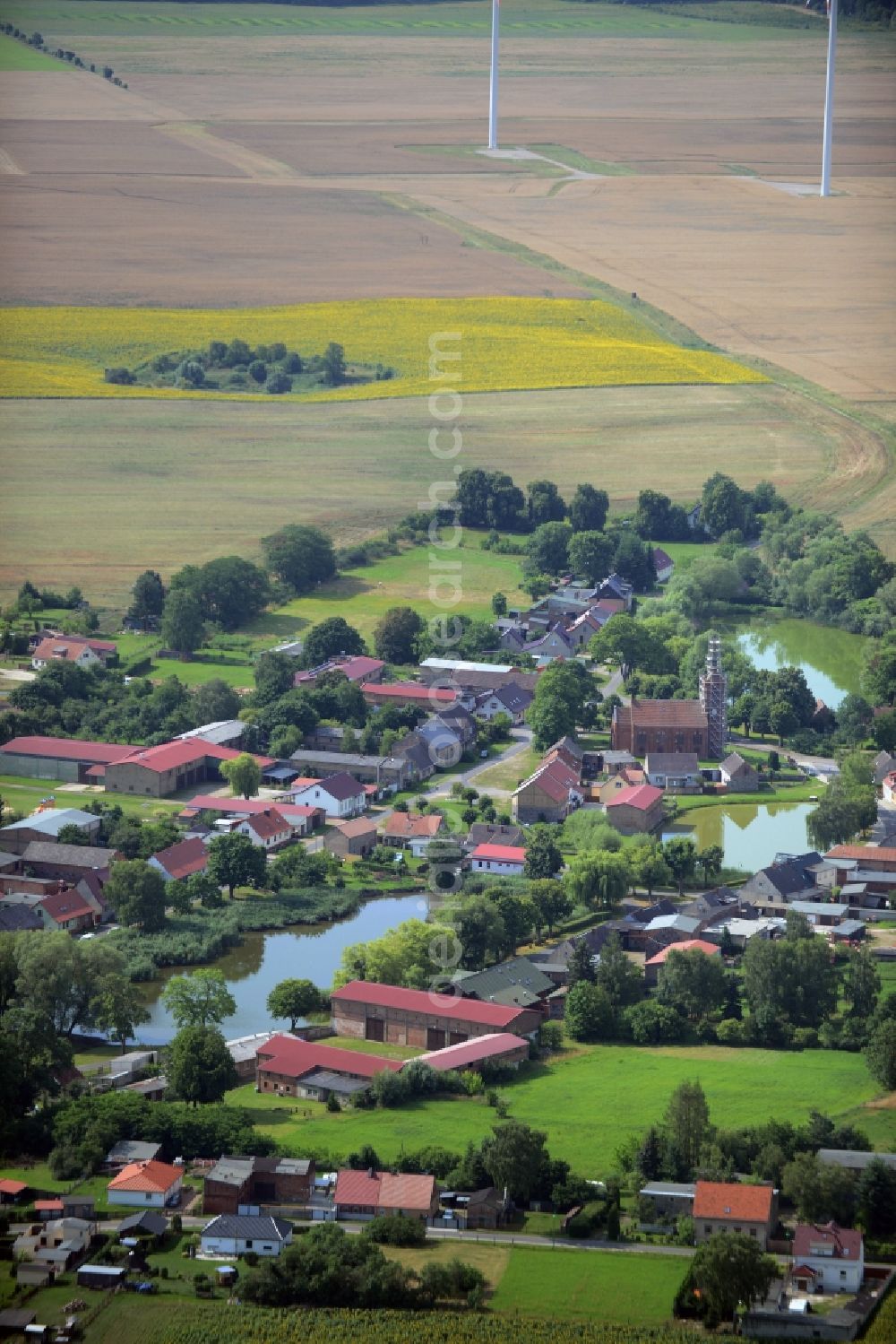 Aerial photograph Beiersdorf-Freudenberg - View of the Freudenberg part of the borough of Beiersdorf-Freudenberg in the state of Brandenburg. The borough is located in the county district of Maerkisch-Oderland and consists of two parts. Freudenberg is a village around two ponds in its centre and consists of residential buildings, a church and small farm estates. Wind turbines are located in the background