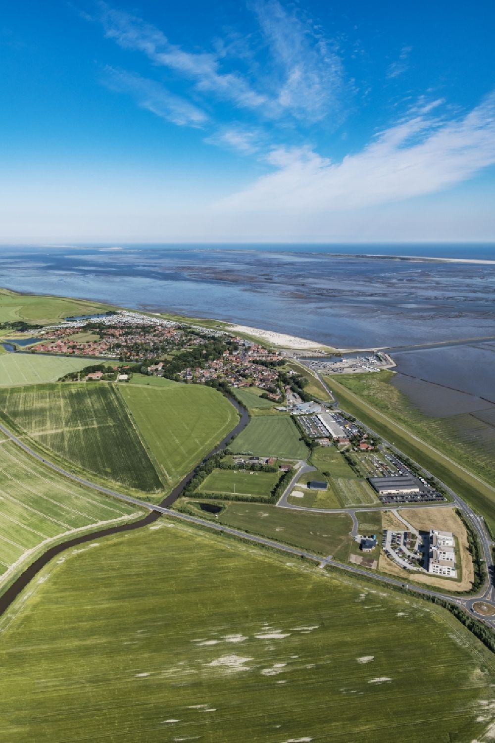 Neuharlingersiel from the bird's eye view: East Frisian Coast in Neuharlingersiel in the state of Lower Saxony. The borough of Neuharlingersiel is located in Harlinger Land in East Frisia on the North Sea shore. The coastal line consists of the Lower Saxony Wadden Sea which has been named a UNESCO world heritage site in 2009. The landscape is characterised by Wadden Sea, agriculture and fields
