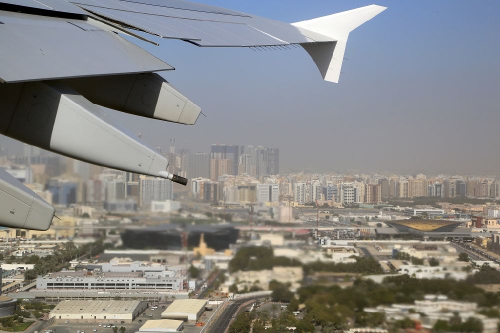 Aerial image Dubai - Airliner - Passenger aircraft Airbus A380 at the start and climb over the airport in Dubai in United Arab Emirates. Looking northbound to the Emirate Sharjah