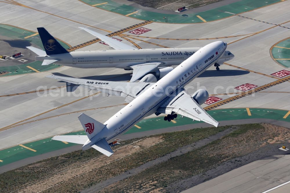 Aerial image Los Angeles - Airliner - Passenger aircraft Boeing 777-300 of the airline Air China at the start and climb and crossing aircraft Saudi Arabian Airlines HZ-AK19 (Boeing 777 - MSN 41056) over the airport in Los Angeles in California, United States of America