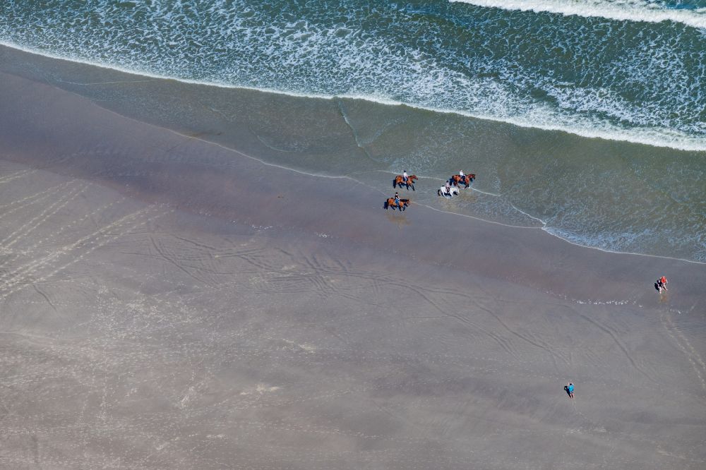 Norderney from above - Riders with their horses in the water and on the sandy beach of the northern beach of the island of Norderney in the state of Lower Saxony, Germany