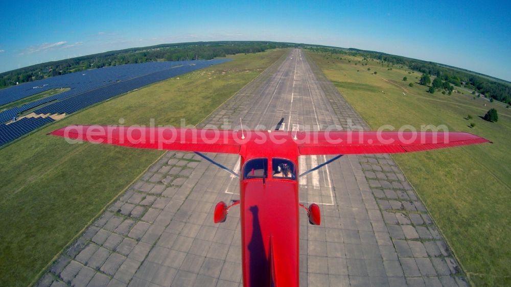 Werneuchen from the bird's eye view: Bright red Cessna 172 D-EGYC of the agency euroluftbild.de in flight over the airfield in Werneuchen in the state Brandenburg, Germany