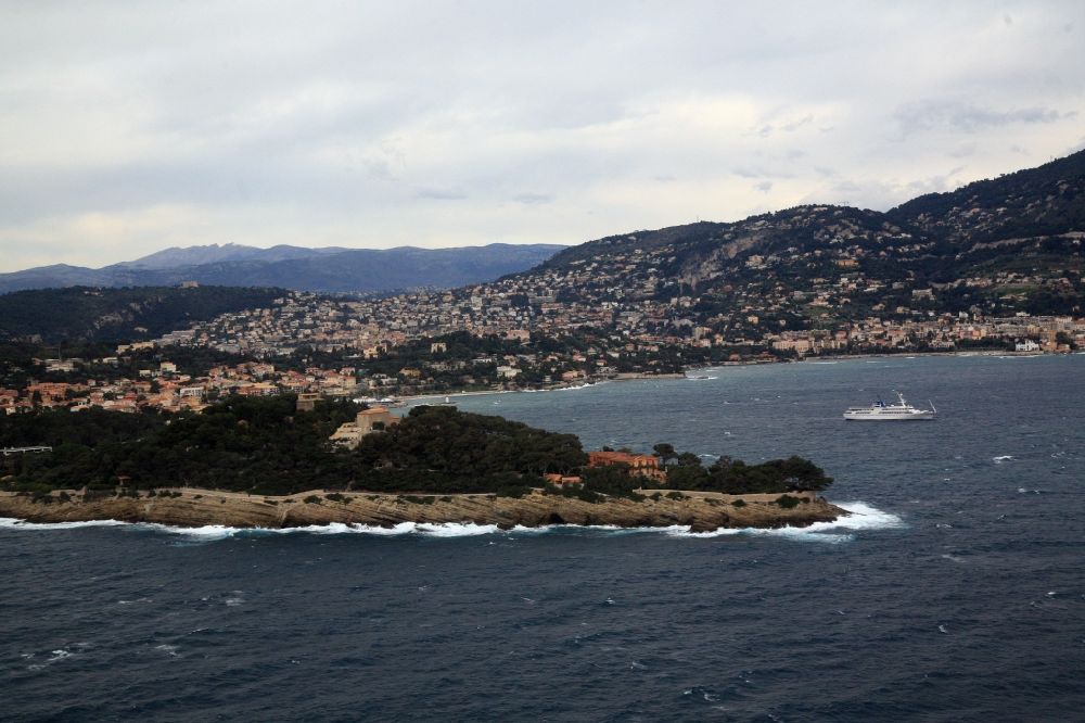 Aerial image Saint-Jean-Cap-Ferrat - Stormy seas in the Mediterranean - Cap-Ferrat peninsula in France. On the coastline in the rear, the towns of Villefranche-sur-Mer and Beaulieu-sur-Mer. The surf strikes the shore