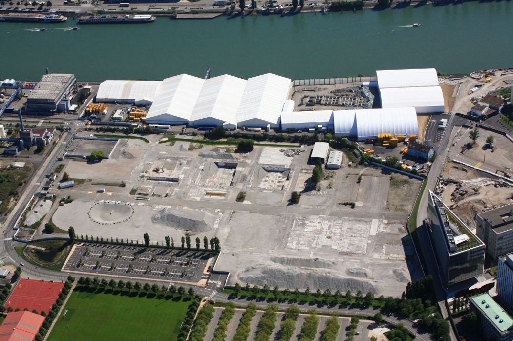 Aerial photograph Huningue - Directly on the border to Switzerland the pharmaceutical company Novartis in Huningue in France rehabilitates the site of a former industrial wastewater treatment plant. The restoration work is carried out under tents to prevent odors and dust contamination. The excavation of contaminated material is transported by ship on the Rhine