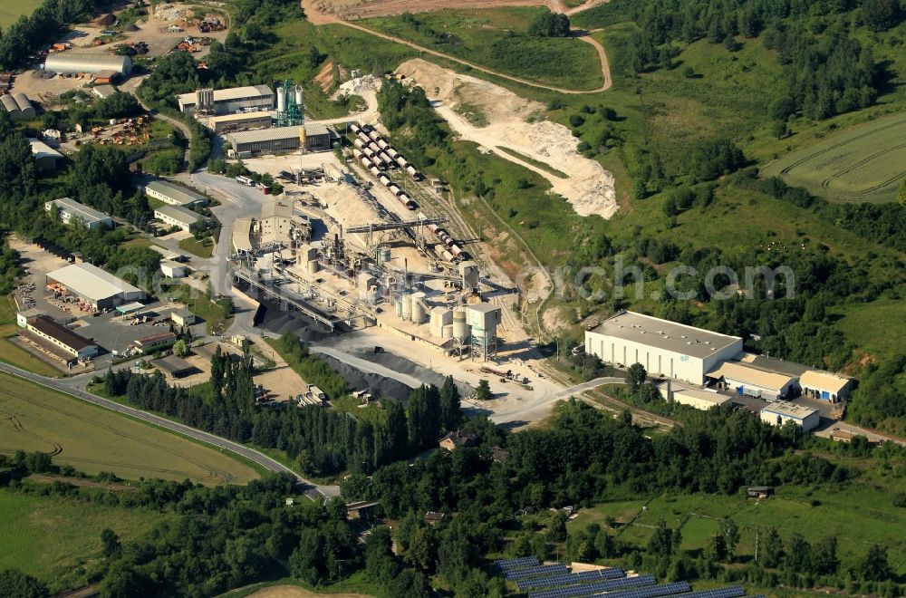 Wünschendorf/Elster from above - On the northern outskirts of Wuenschendorf / Elster in Thuringia dolomite GmbH operates a shaft furnace. In this production plant burnt dolomite for metallurgy and lime are prepared for agriculture. Products and raw materials stored in stockpiles. Freight wagons are available on the tracks for loading. In the vicinity of the system have more companies like LS u. WD construction. Garden Market Wuenschendorf GmbH and ALZI Metallveredlung GmbH is located