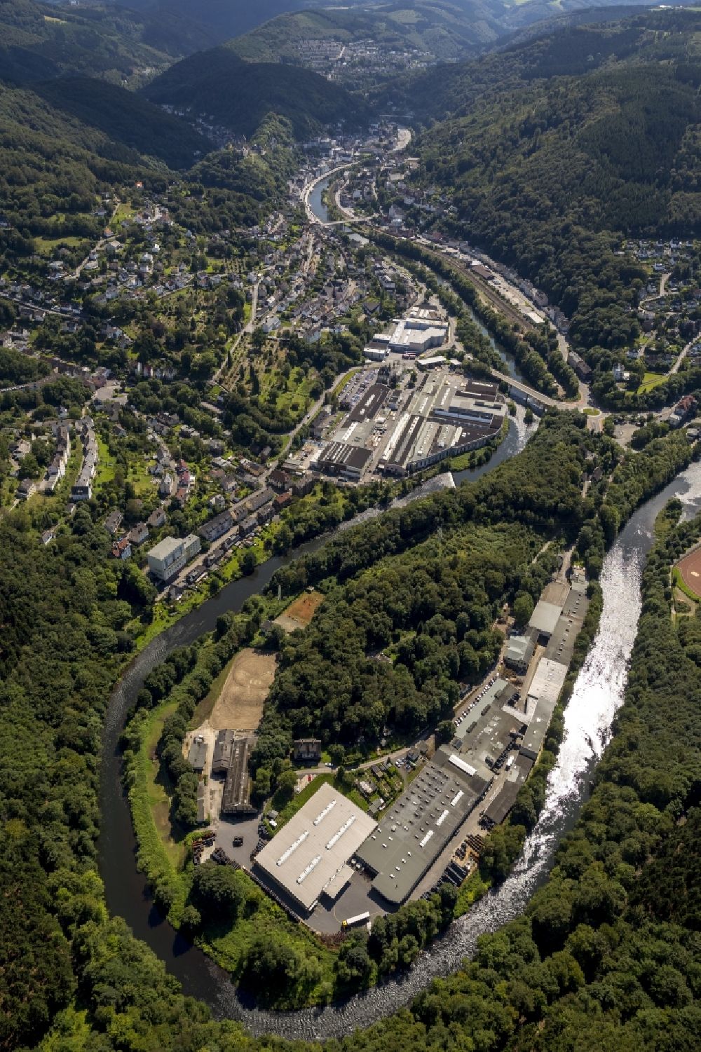 Altena from the bird's eye view: Bight of the river Lenne with a view to a part of the city Altena in the state North Rhine-Westphalia. The river loop creates a peninsula on which several industrial buildings are located along the path Am Huenengraben
