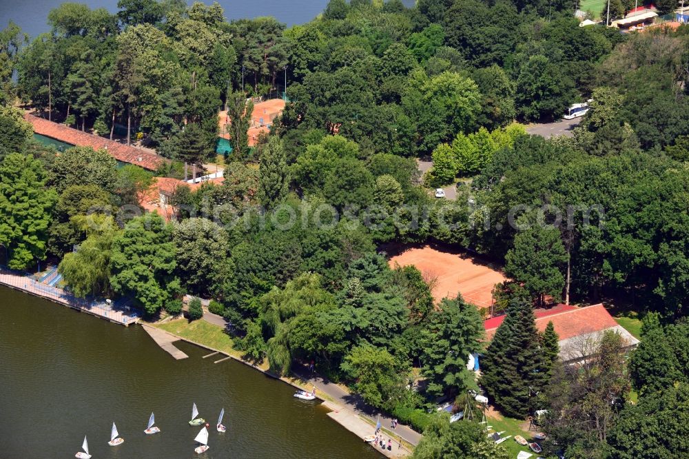 Bukarest from the bird's eye view: Sailing boats and tennis courts on the shore of the lake Lacul Herastrau in the North of Bucharest in Romania. The tennis club Bdk is surrounded by a large park. The lake is used for watersports, boats and sailing