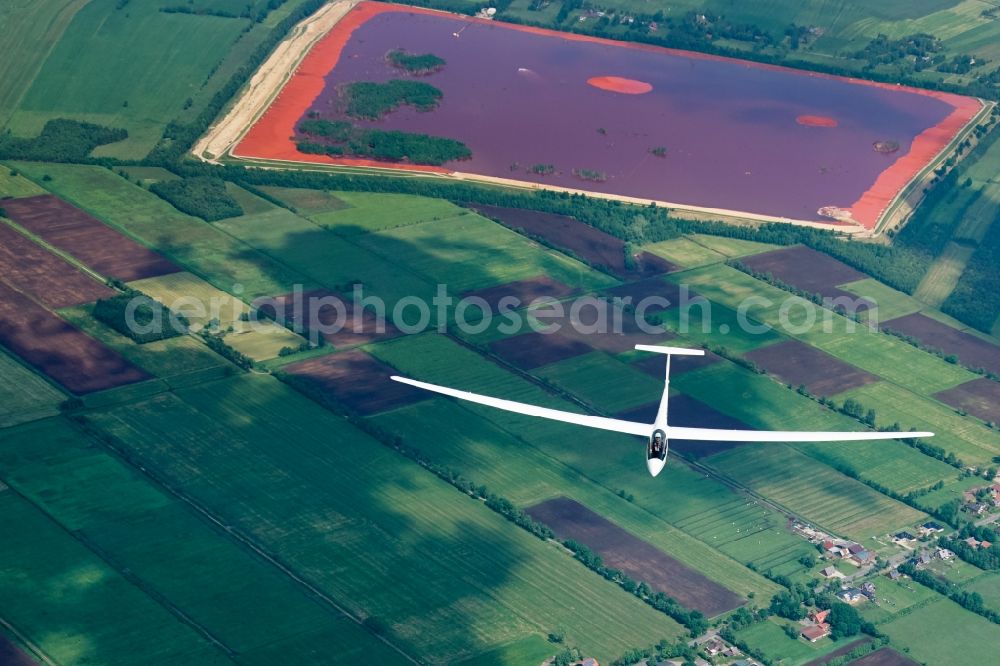 Aerial photograph Stade - High performance glider ASW 20 in flight over the red mud dump near Stade-Buetzfleth in Lower Saxony, Germany. An aluminum production waste product is deposited here
