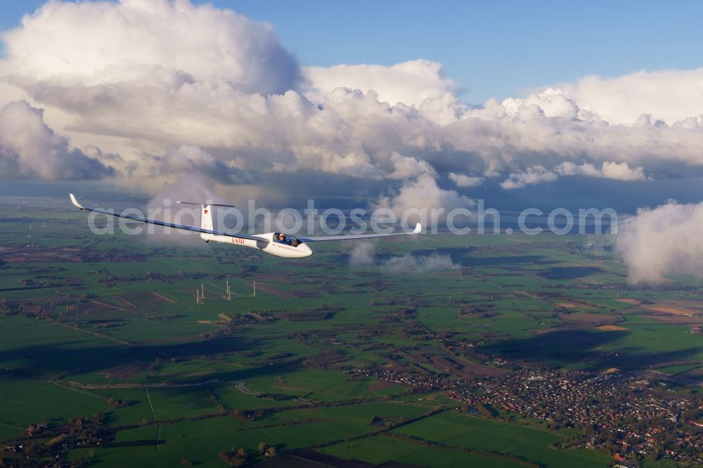 Burweg from the bird's eye view: Glider and sport aircraft LS4 D-4103 flying between huge clouds close to Burweg in the state of Lower Saxony, Germany. This type of glider has been used for many years to train young pilots