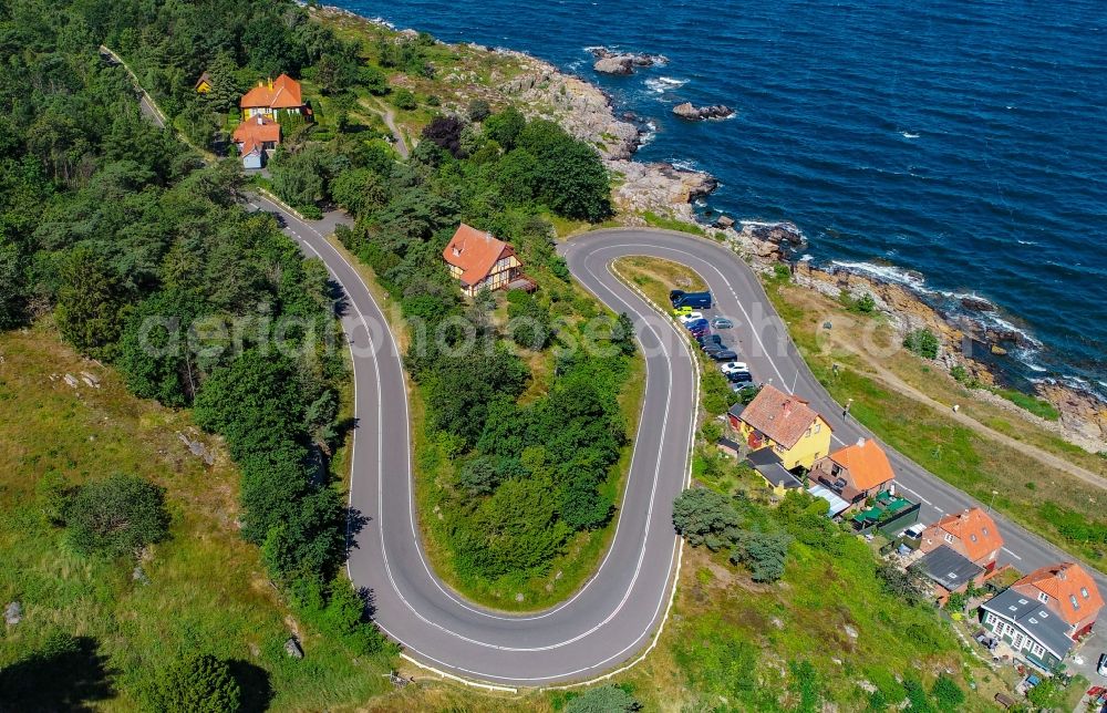 Gudhjem from above - Serpentine-shaped curve of a road guide on the shores of the Baltic Sea in Gudhjem in Region Hovedstaden, Denmark