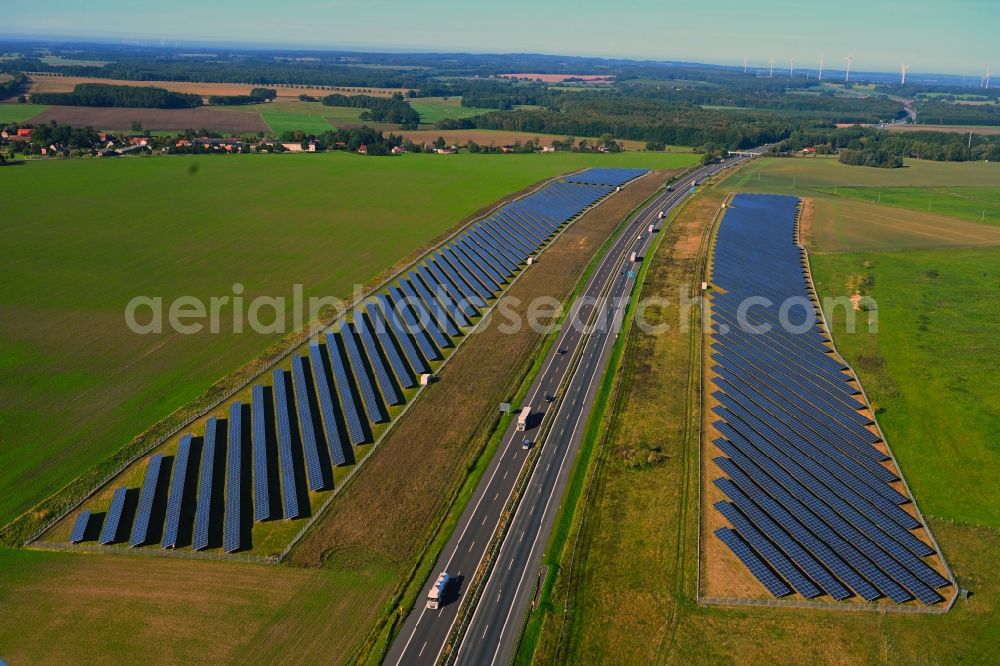 Telschow-Weitgendorf from the bird's eye view: Photovoltaic system and solar power plant - rows of panels on the edge of the lanes of the motorway route and route of the BAB A 24 in Telschow-Weitgendorf in the state Brandenburg, Germany