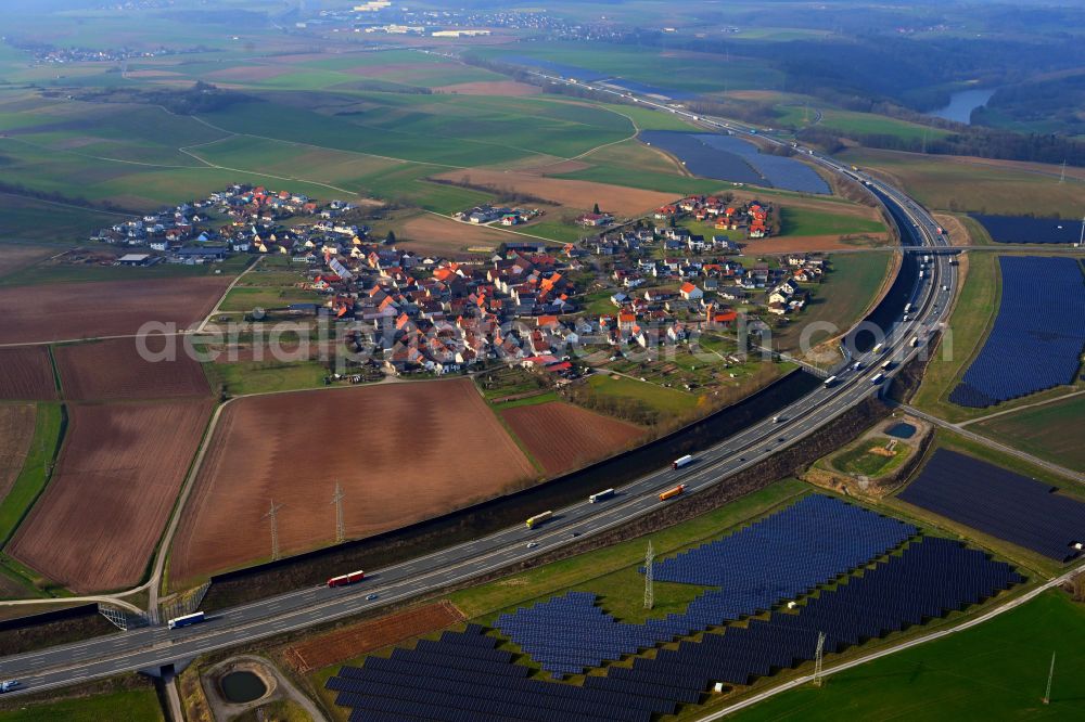 Triefenstein from the bird's eye view: Photovoltaic system and solar power plant - rows of panels on the edge of the lanes of the motorway route and route of the BAB A 3 in Triefenstein in the state Bavaria, Germany