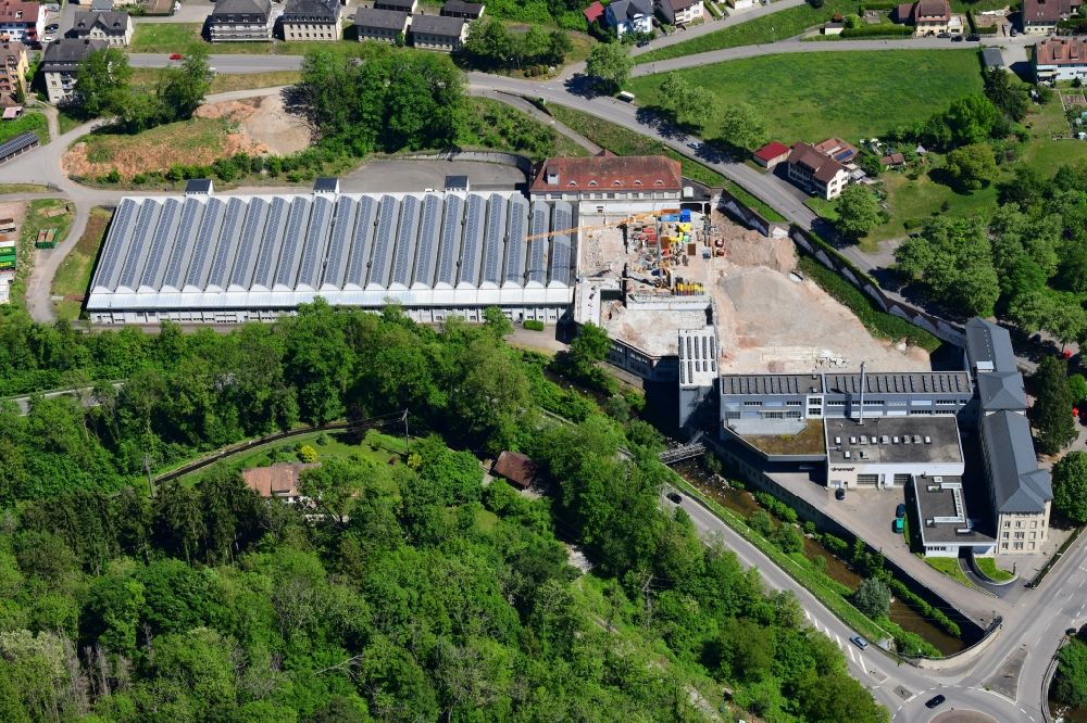 Wehr from the bird's eye view: Panel rows of photovoltaic and solar farm on the company's roof of the former textile company Brennet AG in Wehr (Baden) in the state Baden-Wurttemberg. Part of the area is prepared for new residential buildings