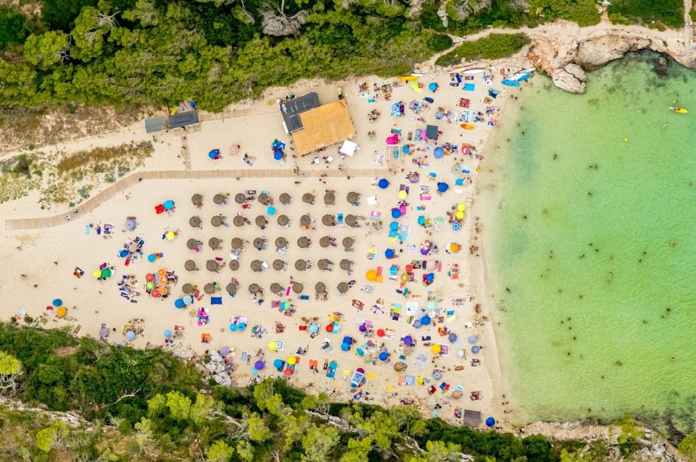 Aerial image Cala Llombards - Row of parasol on the sandy beach ranks in the coastal area Cala Llombards in Cala Llombards in Islas Baleares, Spain