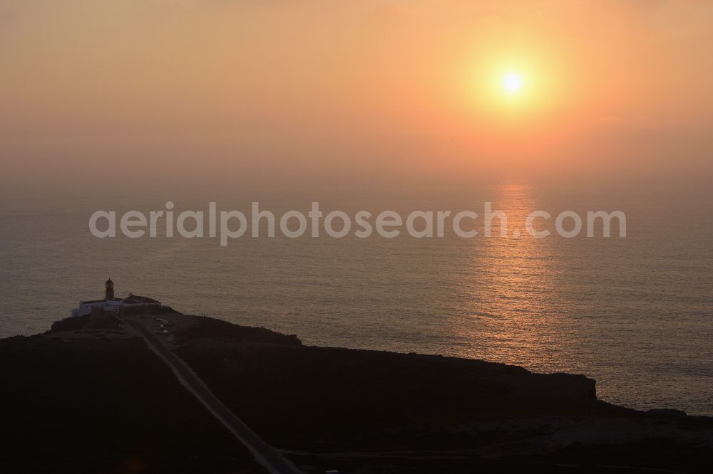 Aerial image Sagres - Sunset at Cabo de Sao Vicente - Cape Saint Vincent near Sagres in Portugal, together with the neighbouring Ponta de Sagres, forms the south-western tip of mainland Europe. Cabo de Sao Vicente is home to a lighthouse whose light cone reaches across the Atlantic Ocean and is considered the most luminous lighthouse in Europe