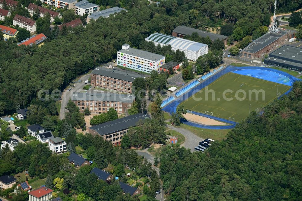 Aerial image Kleinmachnow - Sports facilities of the Berlin Brandenburg International School and residential buildings in Kleinmachnow in the state of Brandenburg. The BBIS includes a football pitch and athletics facilities in a distinct blue colour. Residential buildings and estates as well as a primary school are surrounded by trees and woods