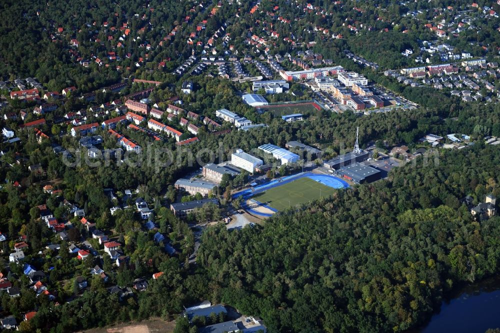 Aerial image Kleinmachnow - Sports facilities of the Berlin Brandenburg International School and residential buildings in Kleinmachnow in the state of Brandenburg. The BBIS includes a football pitch and athletics facilities in a distinct blue colour. Residential buildings and estates as well as a primary school are surrounded by trees and woods