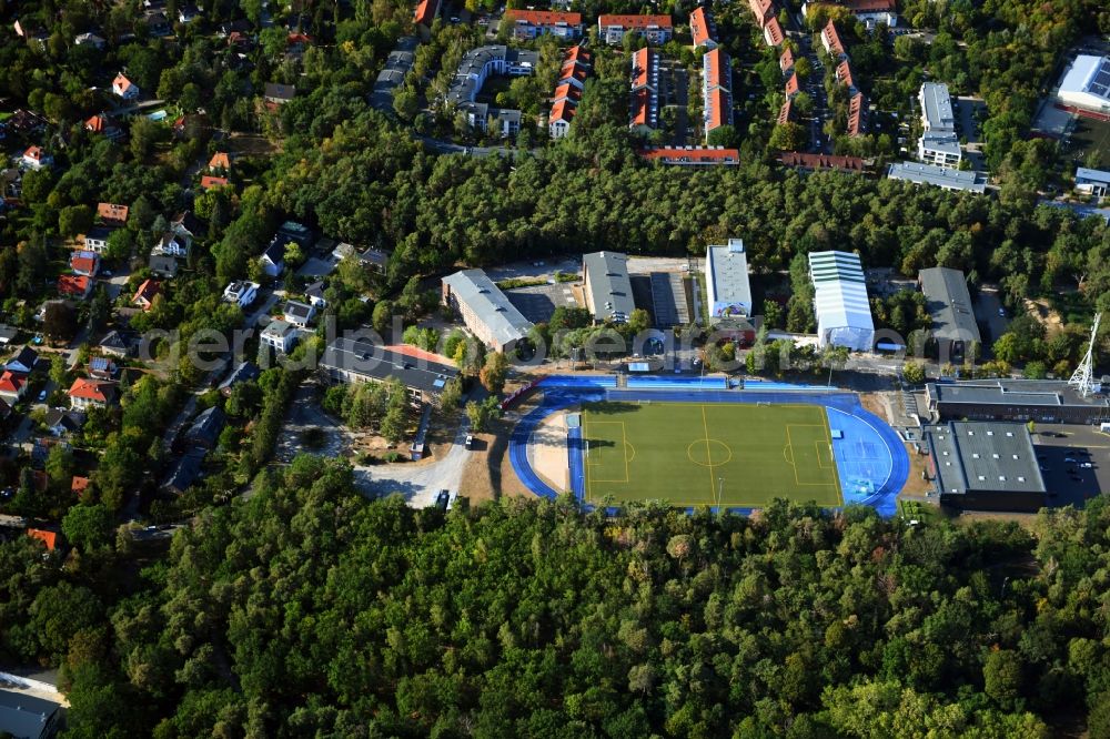 Kleinmachnow from above - Sports facilities of the Berlin Brandenburg International School and residential buildings in Kleinmachnow in the state of Brandenburg. The BBIS includes a football pitch and athletics facilities in a distinct blue colour. Residential buildings and estates as well as a primary school are surrounded by trees and woods