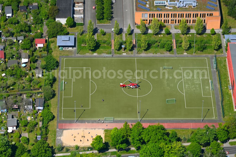 Berlin from the bird's eye view: Sports grounds and football pitch with rescue helicopter employed for on emergency medical mission on street Gustav-Adolf-Strasse in Berlin, Germany