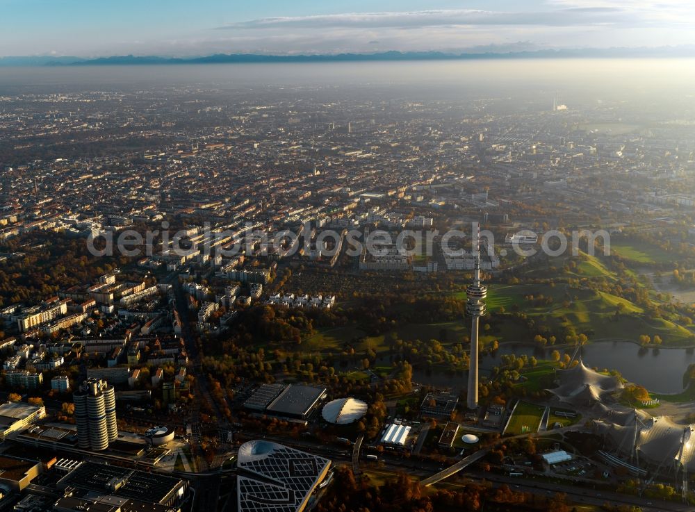 Aerial image München - Cityscape of Munich in the free state of Bavaria. In the foreground lies the Olympic Park. The TV and radio tower Olympiaturm is especially distinct and one of the landmark sites of the city. Located in the background are the city of Munich and mountains of the Alps
