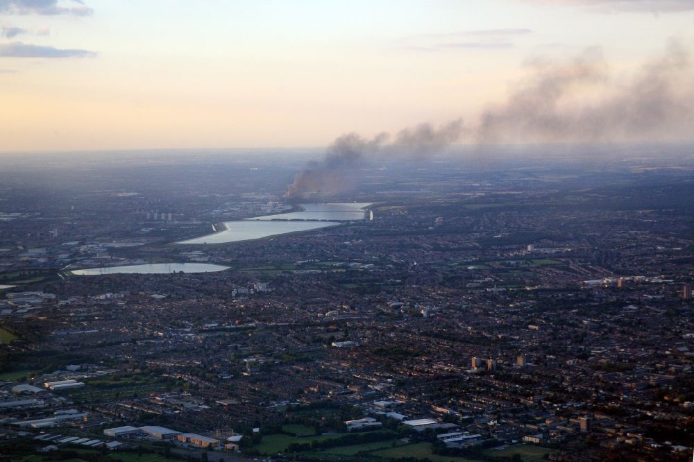 Enfield Town from the bird's eye view: Riots and excesses by young people in and around London set houses and warehouses on fire. Columns of smoke rising into the evening sky. Viewed from an airliner, departet at London City airport