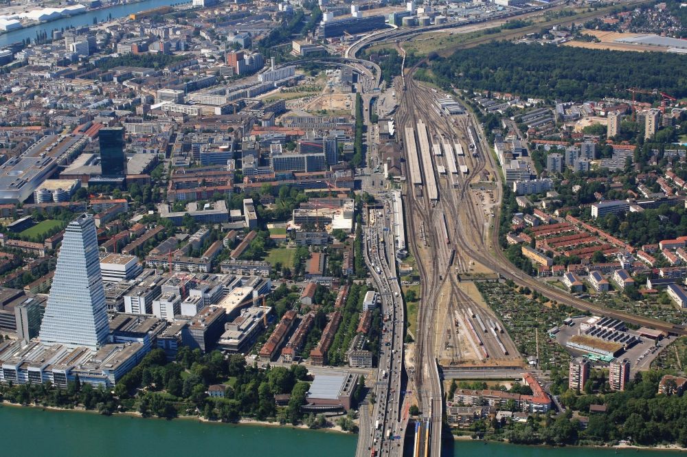 Basel from the bird's eye view: District Kleinbasel in the urban area in Basel, Switzerland. Overlooking the A3 motorway, the four-lane railway line for the NEAT Alpine transit, the skyscraper of the pharmaceutical company Roche, the trade fair complex and the German railway station with the railway tracks 