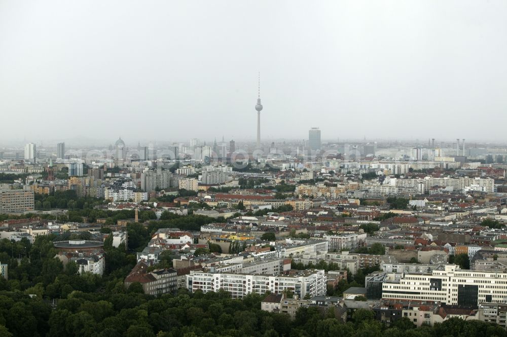 Berlin from above - From Hasenheide Park in the borough of Neukoelln, the view over the densely built-up residential areas of the Kreuzberg district of Berlin in the state of Berlin. Old and new apartment blocks stand between the Urban street and Gitschiner road. At the Fichte Street stands the colossal monument of bunker Fichtebunker. Originally built as a gas tank he offered the 2nd World War, thousands of people take refuge in bomb attacks. In the background the skyline of Berlin's Mitte is seen. The Berlin TV Tower and the ParkInn Hotel at Alexanderplatz are visible from afar