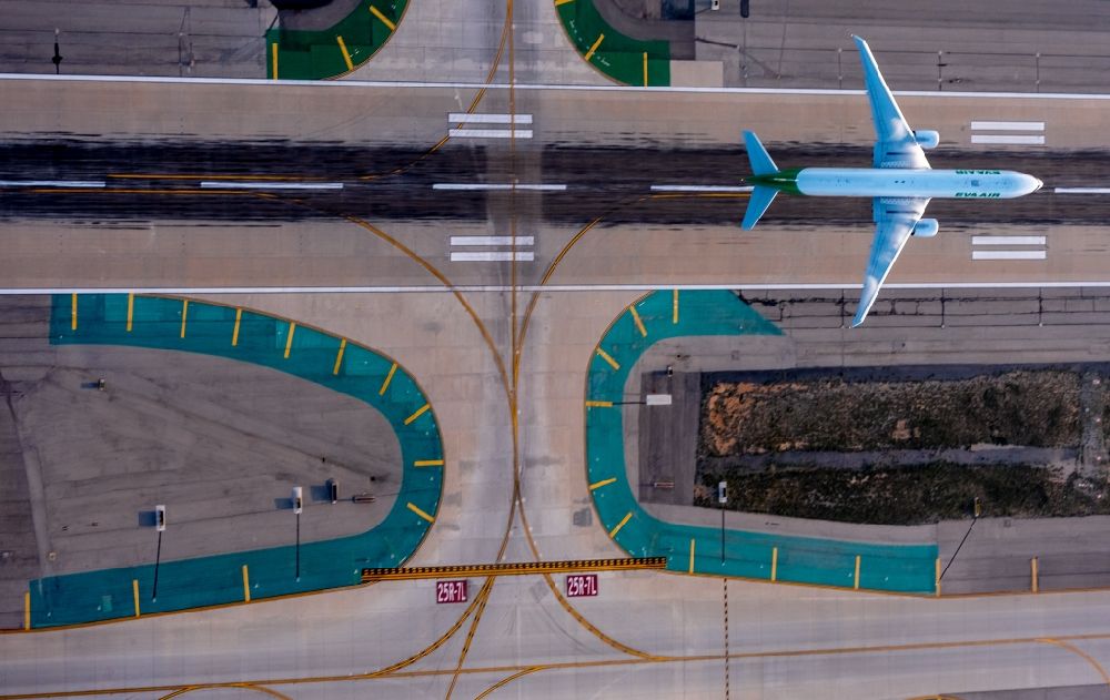 Los Angeles from the bird's eye view: Starting passenger jet on a runway of Los Angeles International Airport LAX in sunset in Los Angeles in California, USA