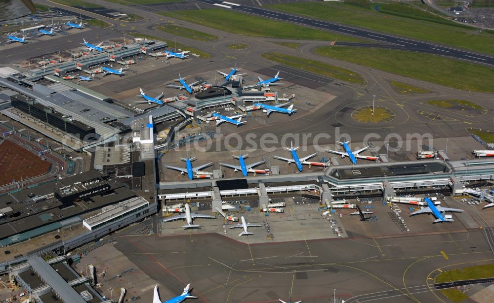 Schiphol from the bird's eye view: Blue passenger aircraft of KLM Royal Dutch Airlines decommissioned at the handling buildings and terminals on the grounds of the airport in Schiphol in Noord-Holland, the Netherlands