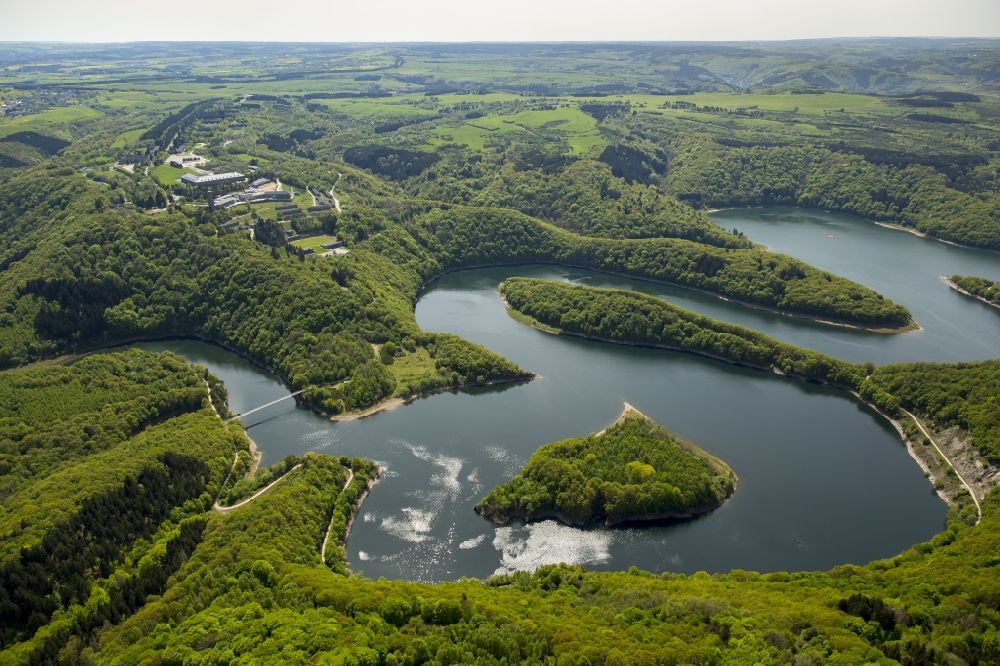 Schleiden from above - Dam and shore areas at the lake Urfttalsperre near Schleiden in the state North Rhine-Westphalia. In view of the complex of buildings of the former Nazi Ordensburg Vogelsang, later barracks of the Belgian armed forces and today's Meeting Centre International Place in the Eifel National Park