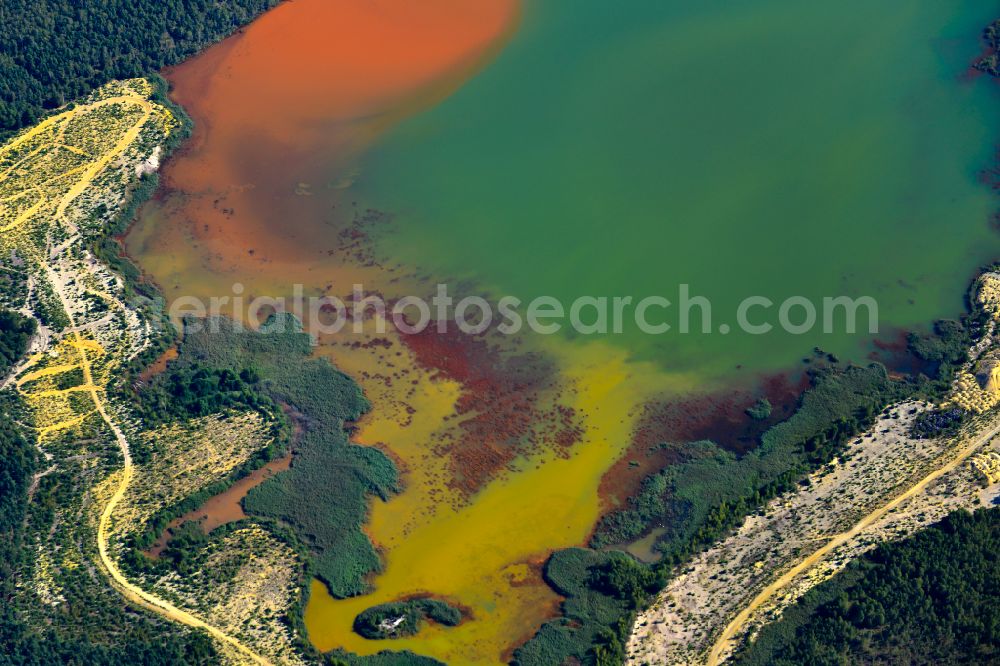 Schwarzheide from the bird's eye view: Pond water surface and pond oasis with brightly colored discharges from the nearby chemical industry and sediment deposits in Schwarzheide in the state of Brandenburg, Germany