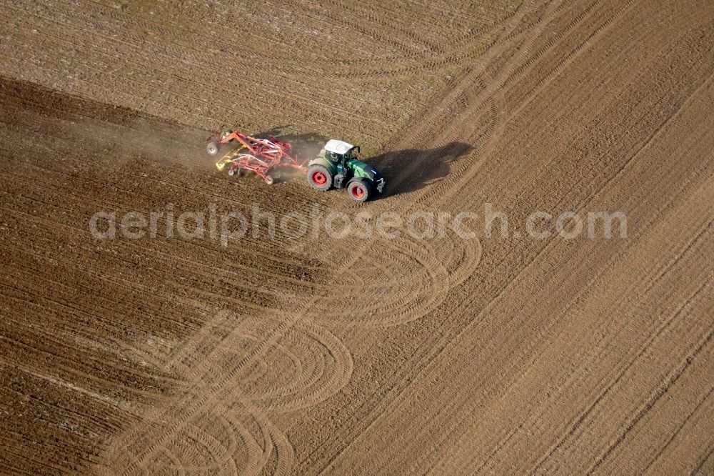Aerial image Friedland - Plowing and shifting the earth by a tractor with plow on agricultural fields in Friedland in the state Lower Saxony, Germany