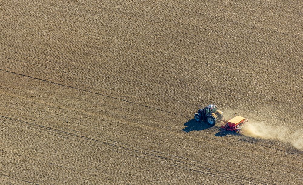 Gehrden from the bird's eye view: Plowing and shifting the earth by a tractor with plow on agricultural fields on street Escherfeld in Gehrden in the state North Rhine-Westphalia, Germany