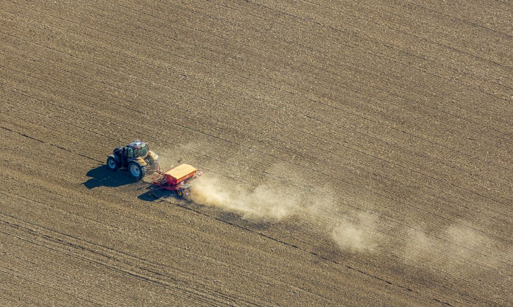 Aerial image Gehrden - Plowing and shifting the earth by a tractor with plow on agricultural fields on street Escherfeld in Gehrden in the state North Rhine-Westphalia, Germany