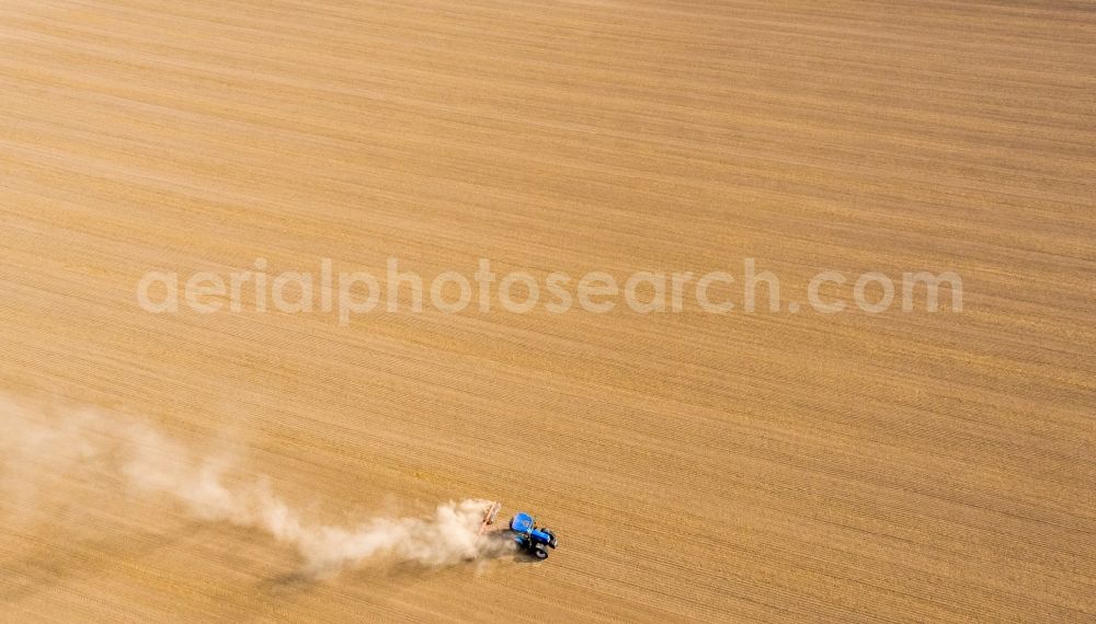 Aerial image Grimma - Plowing and shifting the earth by a tractor with plow on agricultural fields in Grimma in the state Saxony, Germany