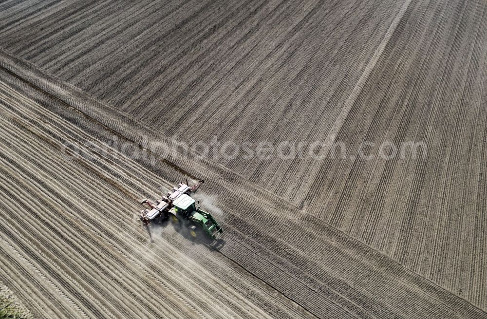 Aerial photograph Haseloff - Plowing and shifting the earth by a tractor with plow on agricultural fields in Haseloff in the state Brandenburg, Germany