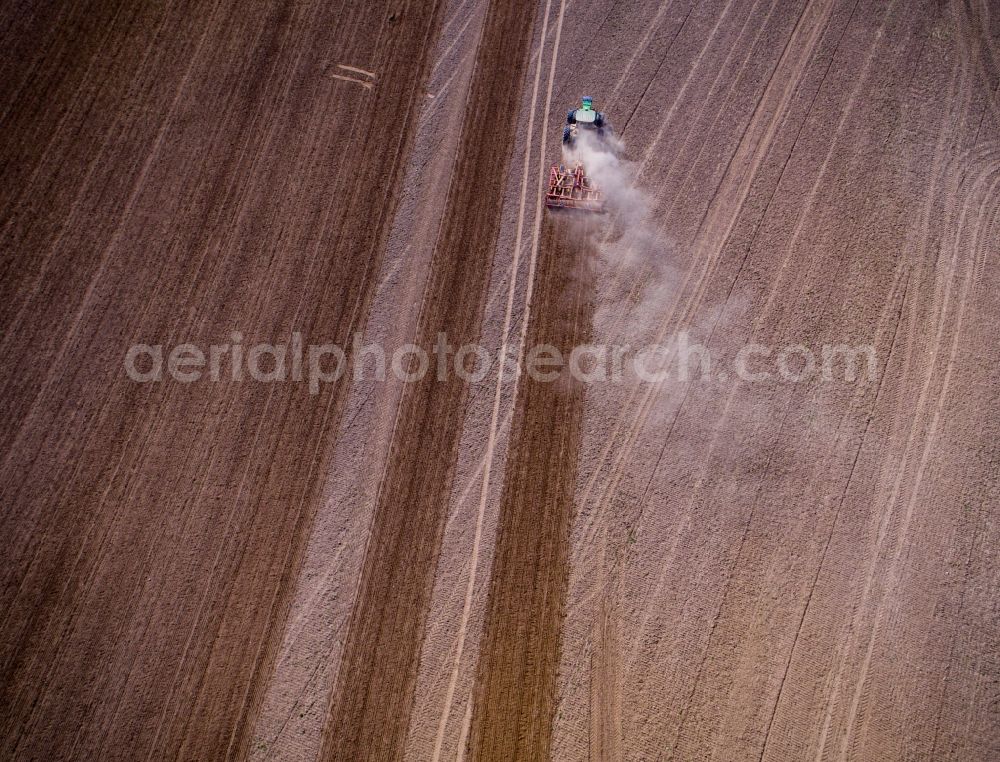 Jürgenshagen from the bird's eye view: Plowing and shifting the earth by a tractor with plow on agricultural fields in Juergenshagen in the state Mecklenburg - Western Pomerania, Germany