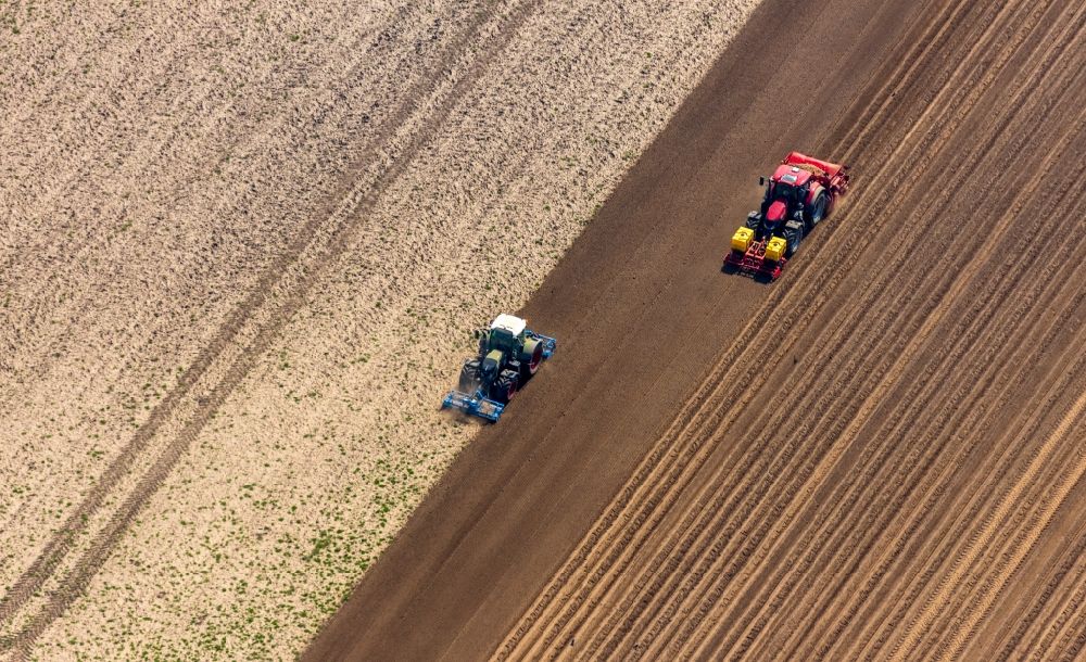 Aerial image Rees - Plowing and shifting the earth by a tractor with plow on agricultural fields in Rees in the state North Rhine-Westphalia, Germany