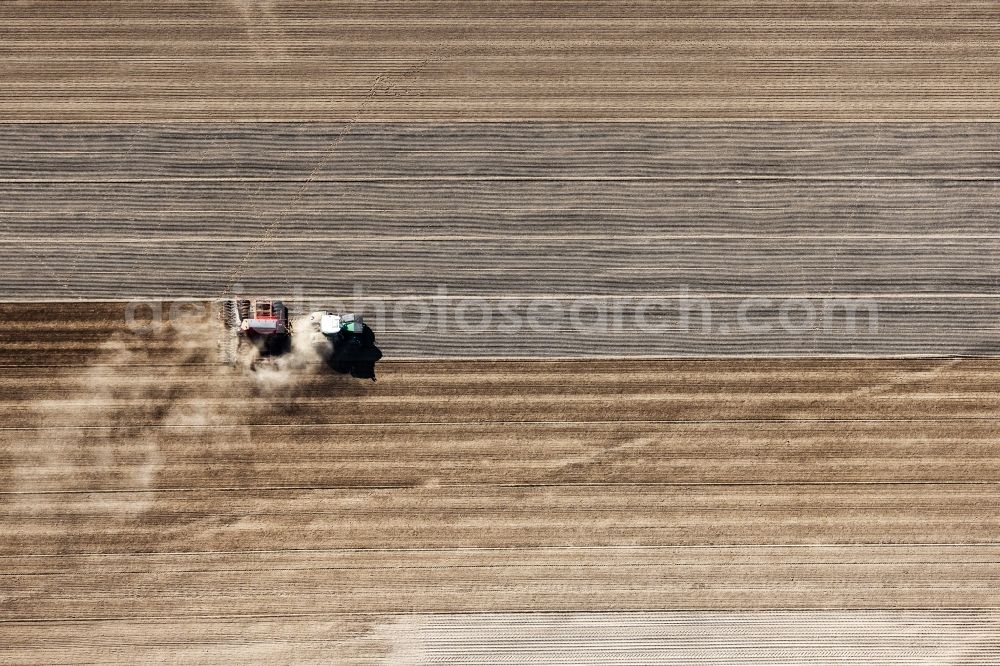 Travenbrück from the bird's eye view: Plowing and shifting the earth by a tractor with plow on agricultural fields in Travenbrueck in the state Schleswig-Holstein, Germany